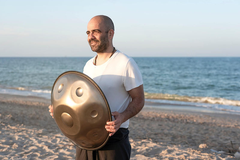 handpan acheter, instrument hang, homme tient un handpan sur la plage